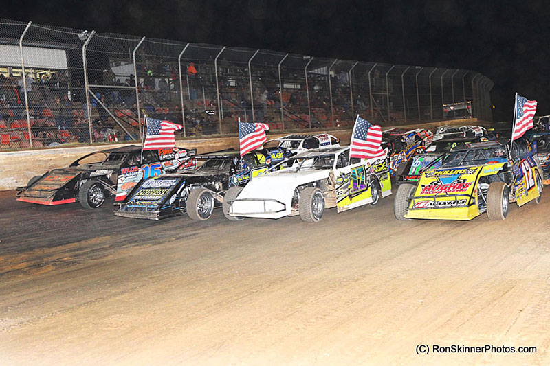 Drivers salute the fans with their traditional four-wide salute on night 3 of 3 of 5th Annual Cajun Clash presented by Horseshoe Bossier City at the Ark-La-Tex Speedway in Vivian, La. Carrying the American flags from left to right are Chris Henigan, Stormy Scott, Jake Gallardo and Jason Hughes. (Scott Burson Photo)