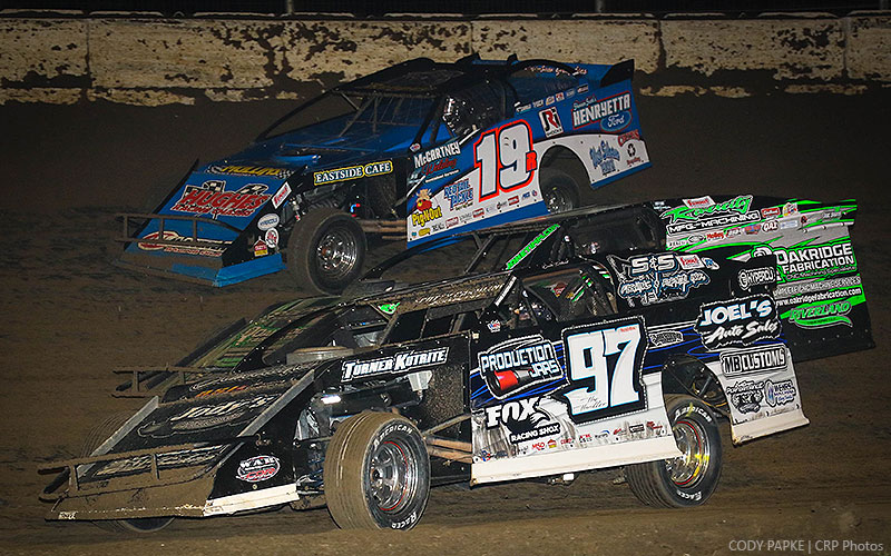 Cade Dillard (97) and Ryan Gustin (19R) split the lapped car of Jake Timm while battling for the lead during the main event at the King of America VII Modified Nationals presented by Summit Racing at the Humboldt Speedway in Humboldt, Kan., on Saturday, March 25, 2017.